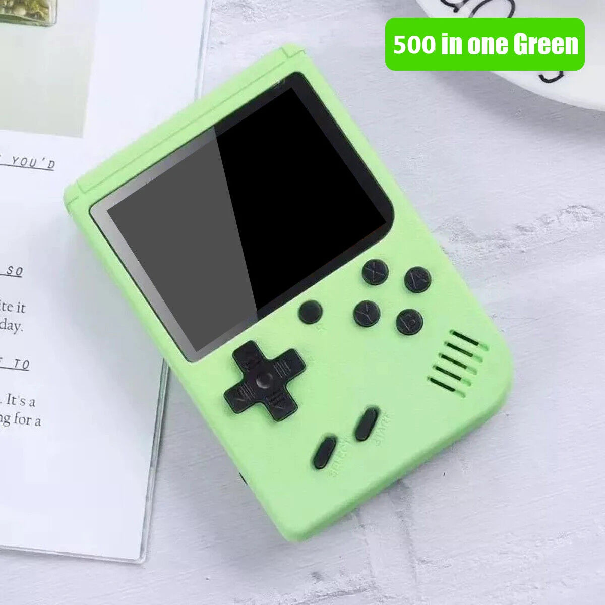 Green handheld gaming console on a light gray surface with text overlay.
